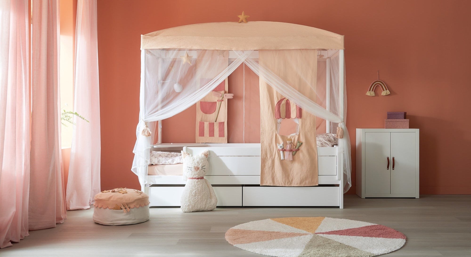 LIFETIME Kidsrooms canopy bed with playful curtains and textile accessories in soft peach tones – ideal for imaginative children's rooms